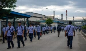 Ilustrasi buruh pabrik di kawasan industri yang menghadapi tekanan ekonomi dan ketidakpastian kerja.