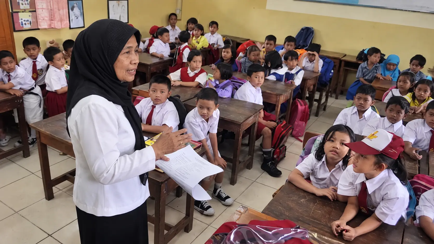 Guru mengajar siswa di ruang kelas